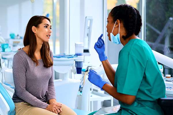 Young woman talking black female dentist during appointment at dental clinic.